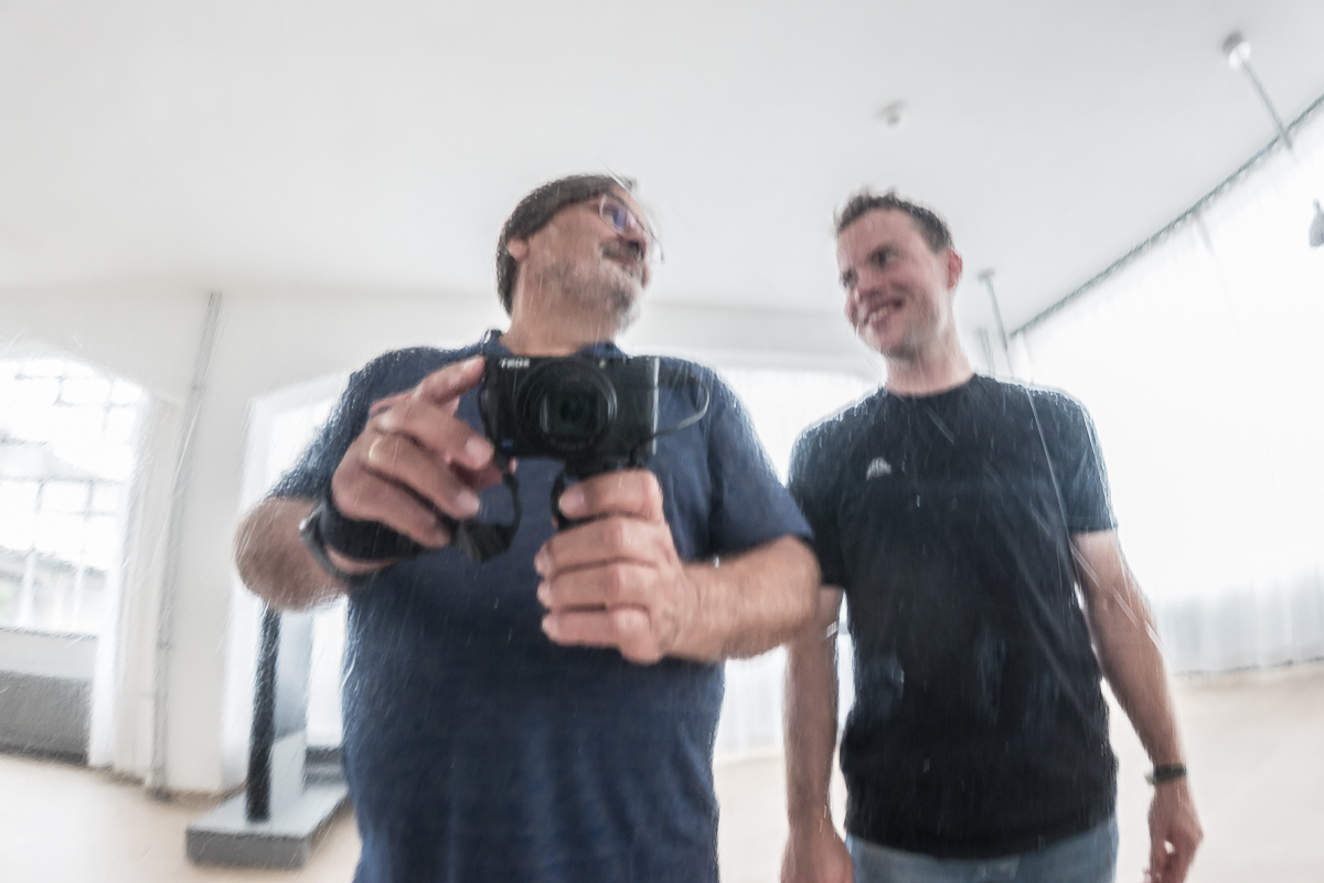 Zwei Männer fotografieren sich in einem Spiegel