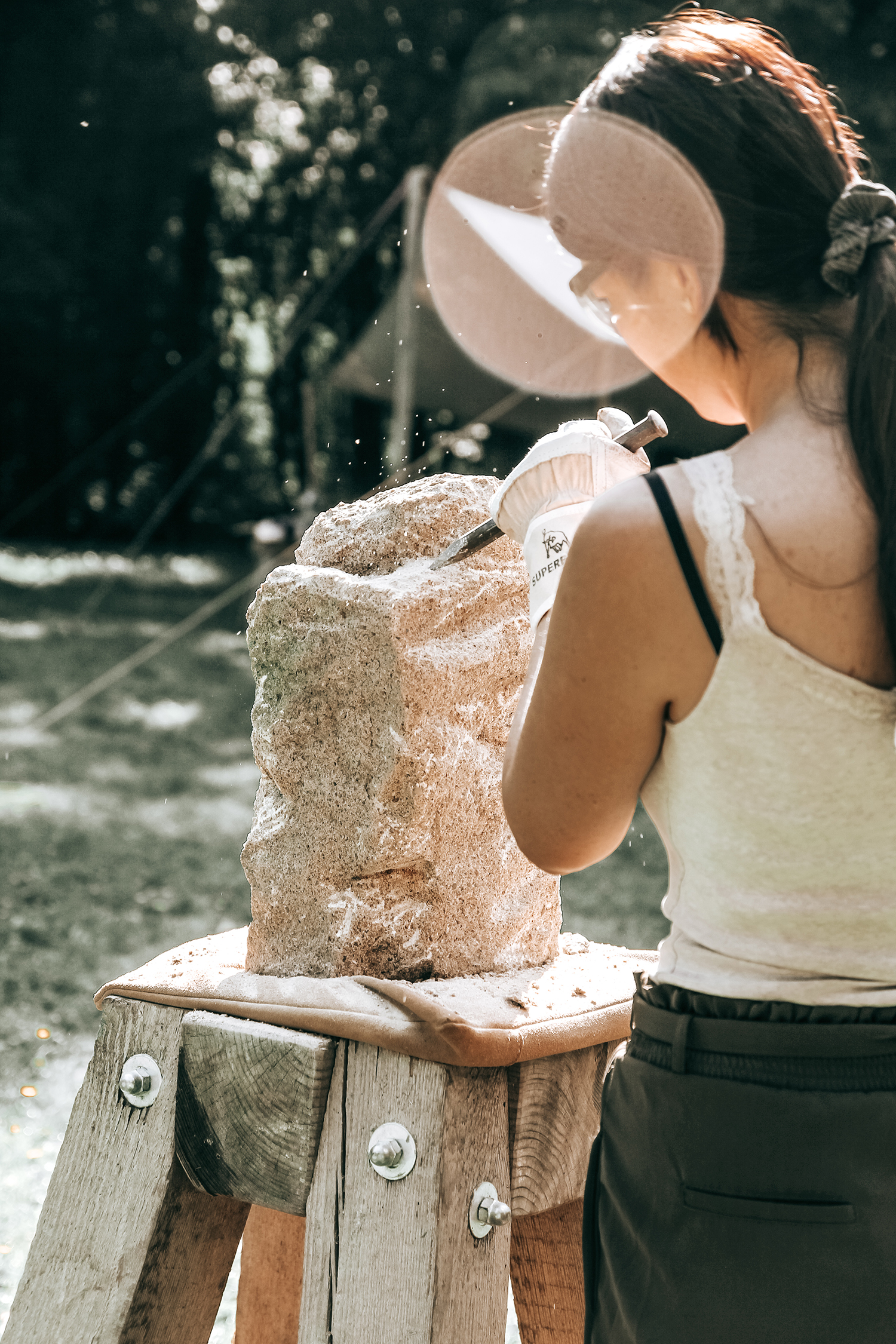 Eine Studentin bearbeitet einen Stein mit Hammer und Meißel